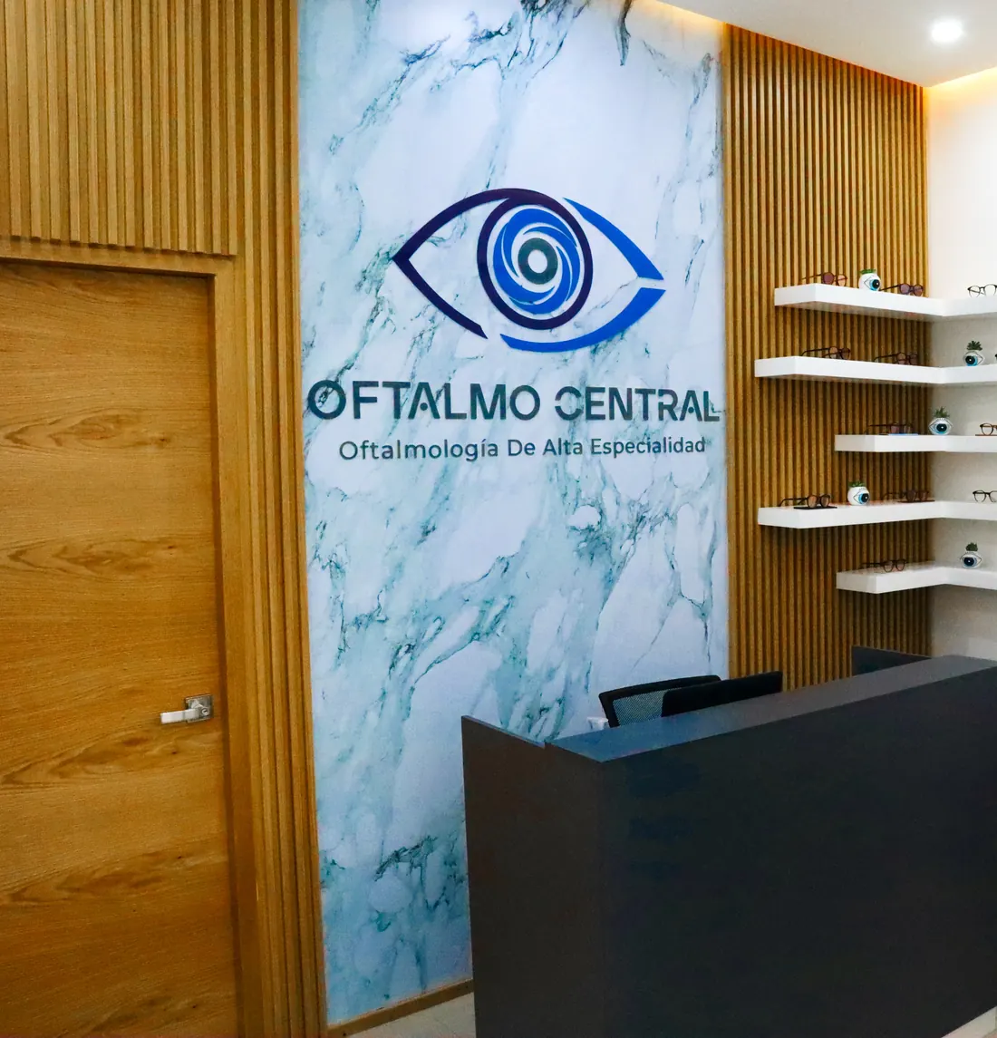 Recepción de Oftalmo Central en Plaza Life Care, Saltillo, con el logotipo sobre un muro de mármol y madera